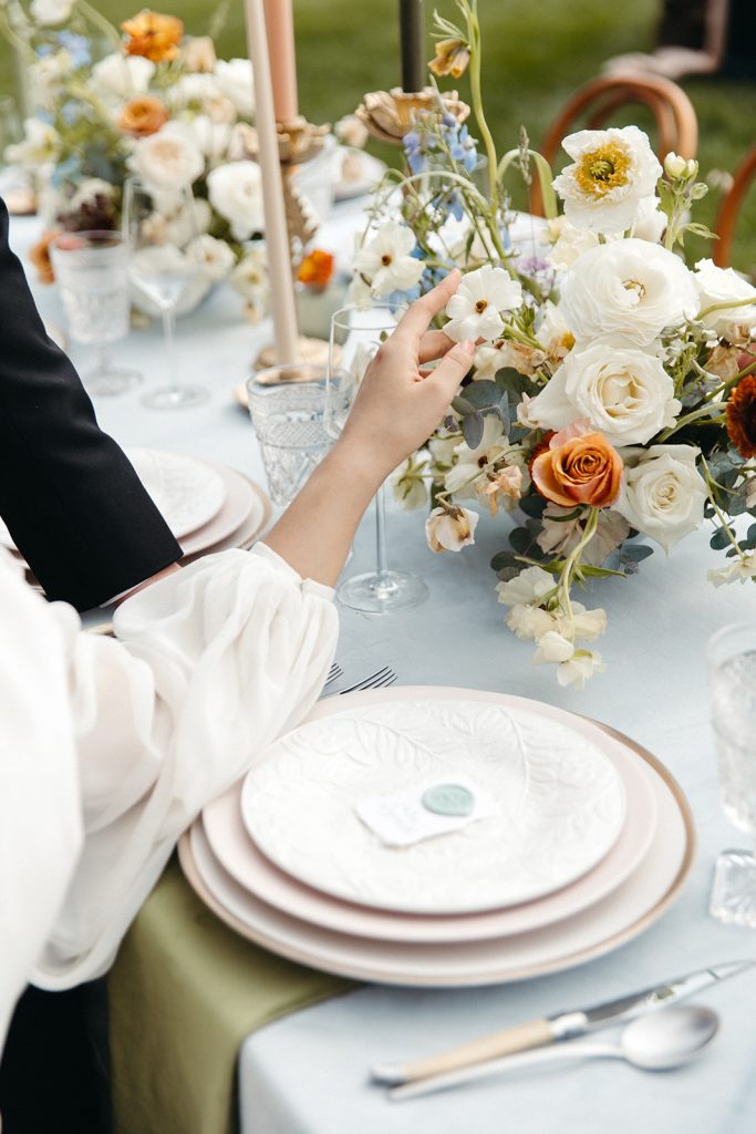 Close up of a bride touching ornate details on the tablescape of her editorial wedding