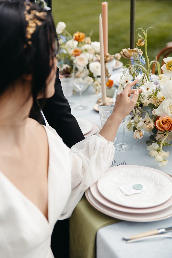 Planning a Villa Wedding: 9 Do's and Don'ts. Bride gazing at and touching the floral arrangement handpicked for their wedding reception