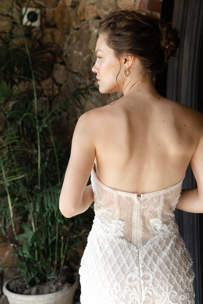 Bride looking off into the distance as she shows off the elegant detailing of her wedding dress