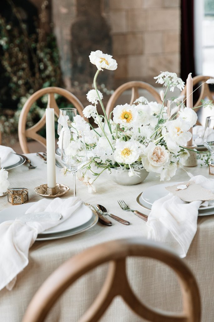 Vibrant photo of the white-themed wedding reception table, with a floral arrangement as a centerpiece