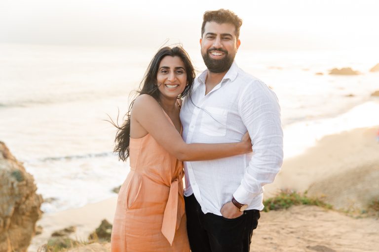 Newly engaged couple smile as the girl wraps her arm around the guy during their engagement shoot at El Matador Beach, photographed by Kyla Jeanette