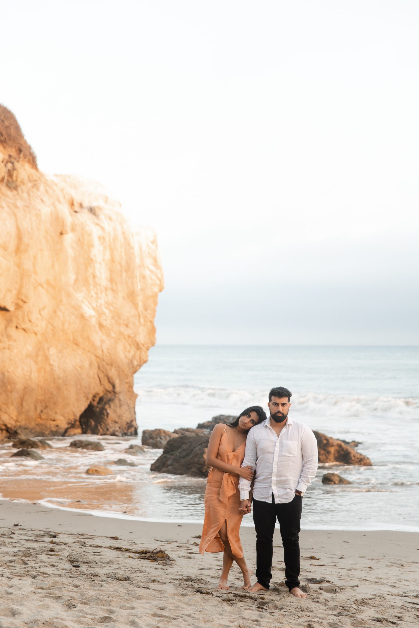 Girl leans her head against the guy’s shoulder as they stand side by side at El Matador Beach shot by Kyla Jeanette