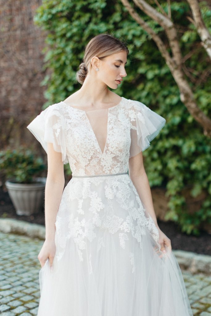 Stunning bride looks down as she touches her classic bridal dress