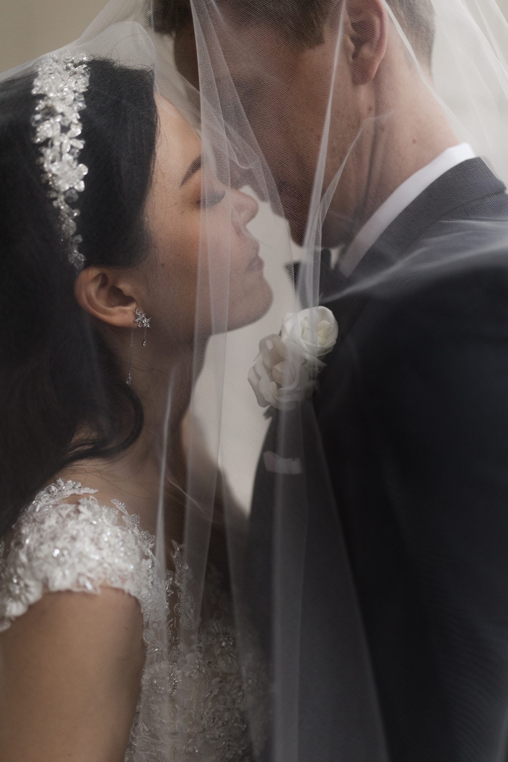 Bride and groom lean in for a kiss under the bride's sheer veil, captured by Kyla Jeanette Photography