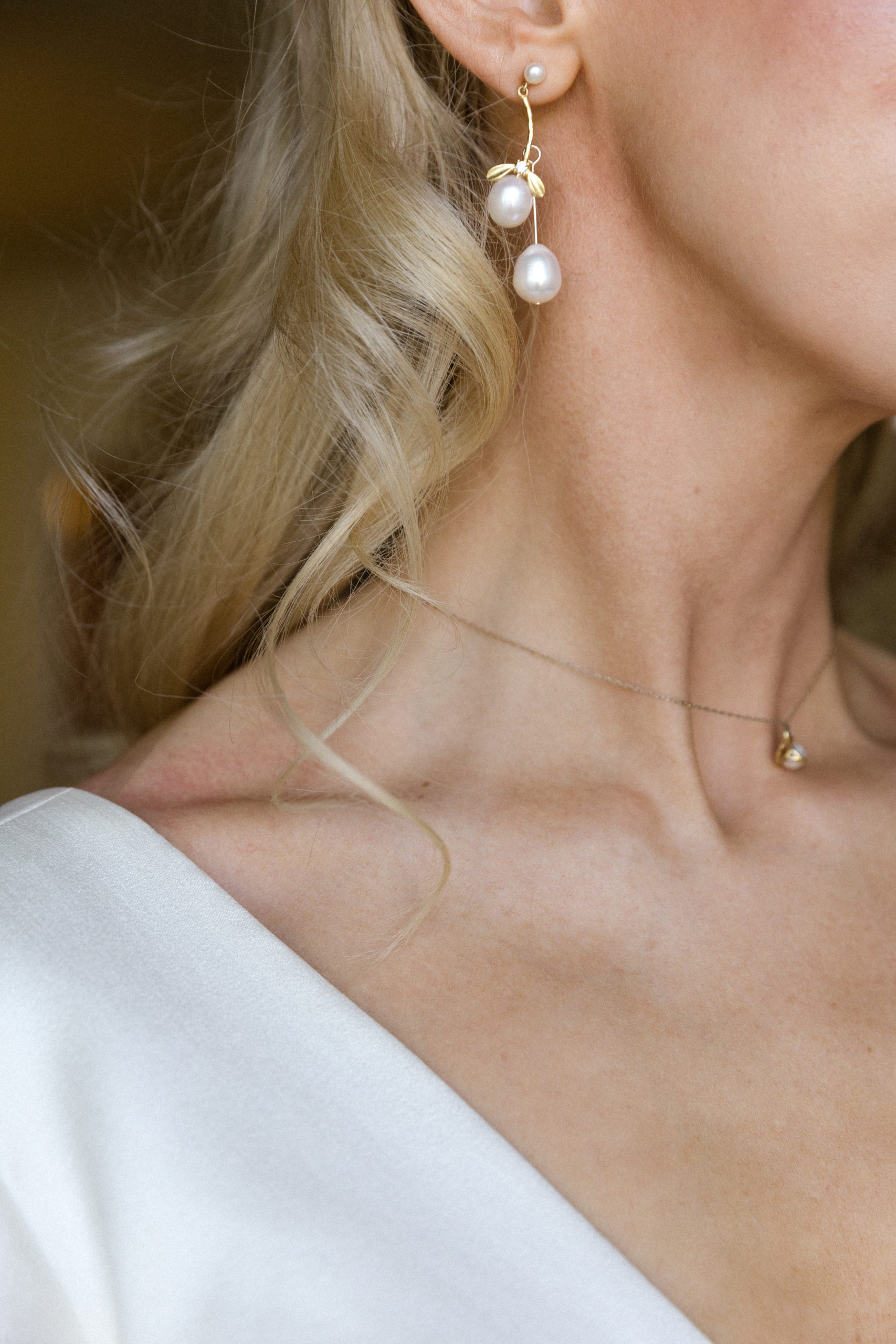 A side photo of an elegantly dressed bride wearing a white dress and dangling earrings