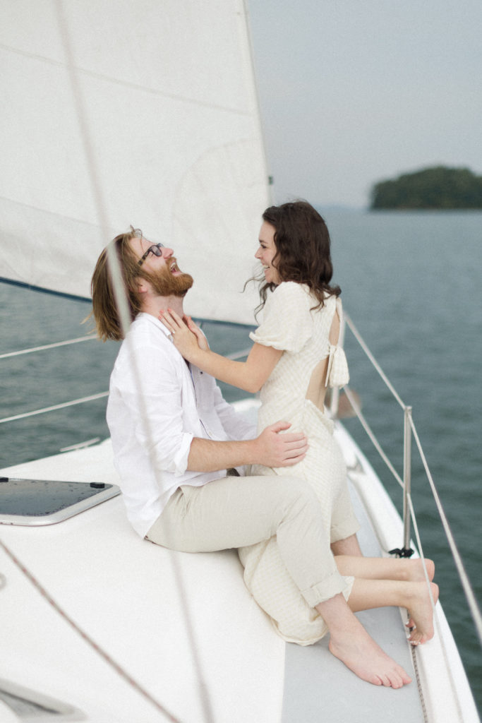 Ethereal Sailboat Engagement Photos in Atlanta, Georgia: Couple sharing laughs on the sailboat, photographed by Kyla Jeanette