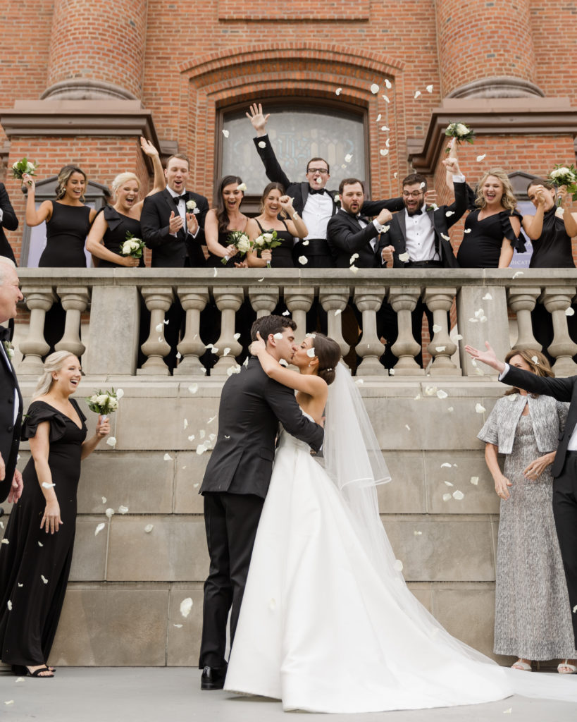 Bride and groom sharing a kiss as their wedding guests shower petals on them during their wedding shoot with Kyla Jeanette Photography