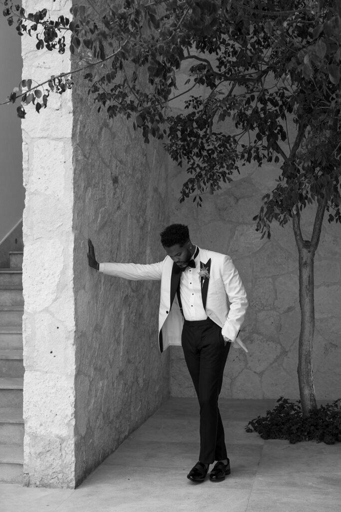 Lee in a tuxedo leaning against a wall
