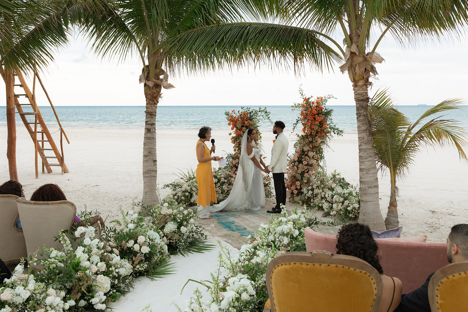 a group of people under a tropical beach for Lauren and Lee's wedding ceremony
